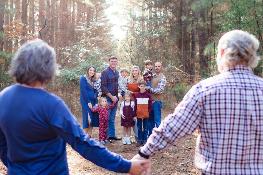 Family standing in golden autumn light at Jetton Park, surrounded by tall trees.
